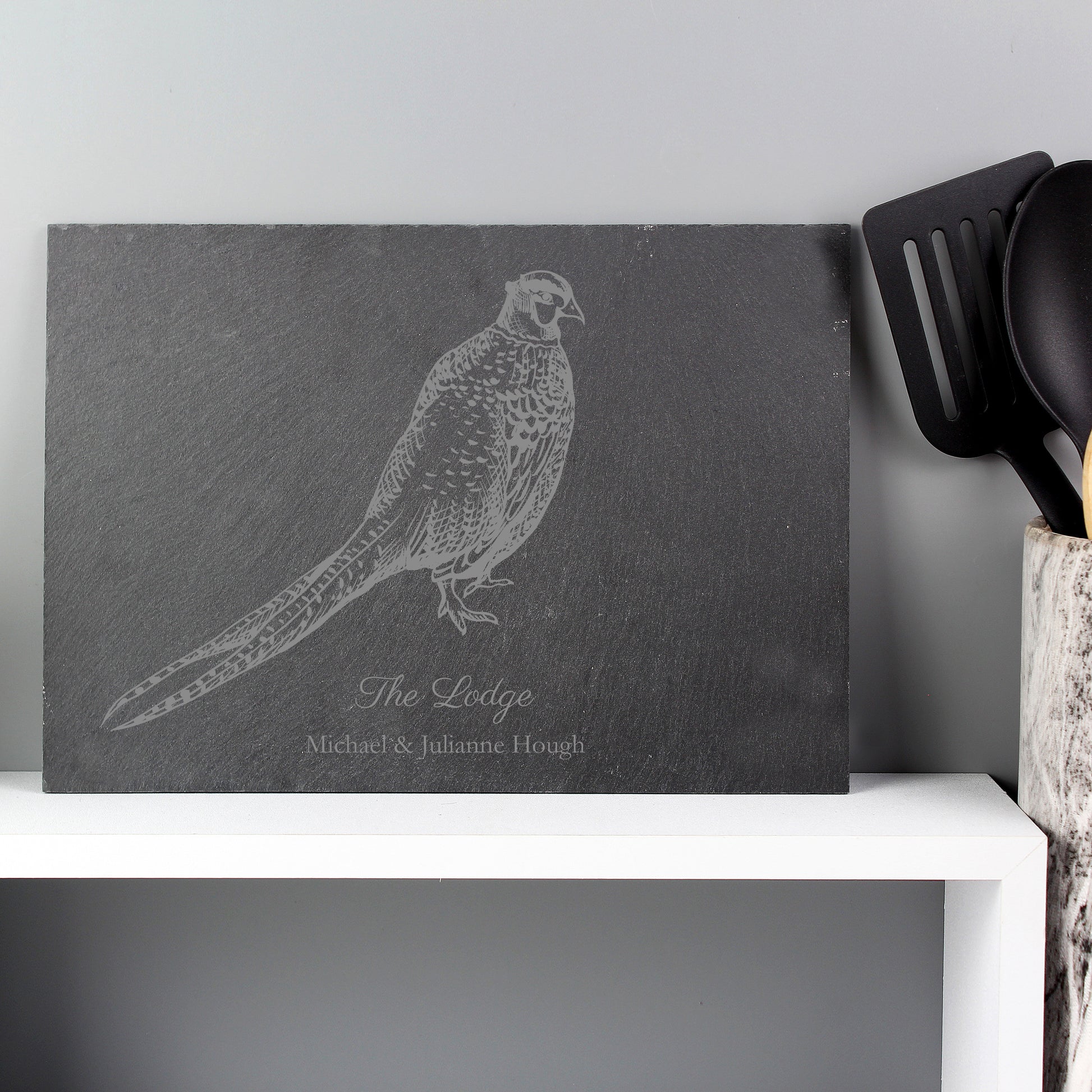 a grey slate placemat feasturing a pheasant design with personalisation below
